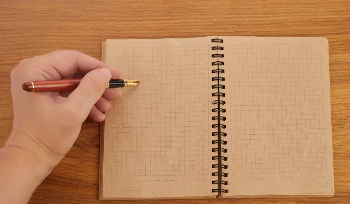 Person writing with her left hand on a notebook