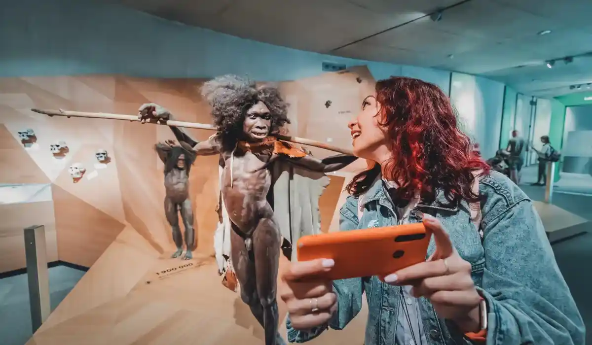Girl is taking a selfie with wax figures of her prehistoric ancestors at the museum of anthropology and science in Germany