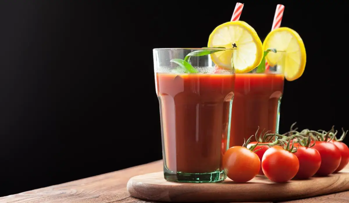 Two glasses of bloody mary with lemon on a tray with tomatoes