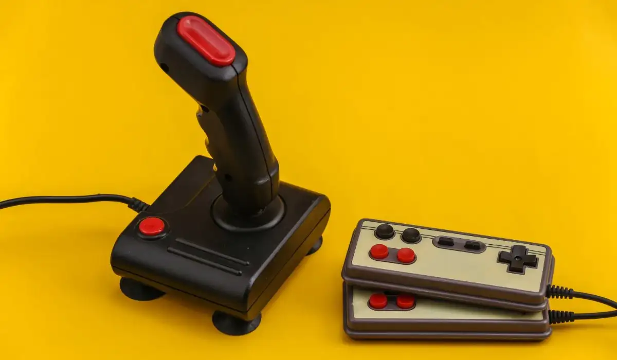 Retro gamepad and joystick on yellow background, 80s games