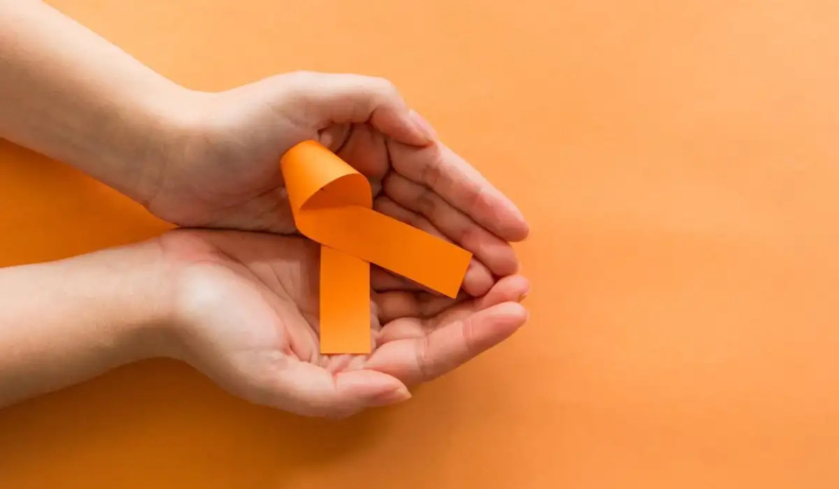 Woman's hands with orange ribbon, self-harm awareness