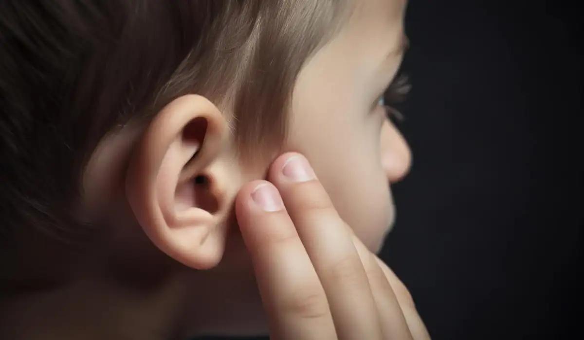 A boy with a finger on his ear