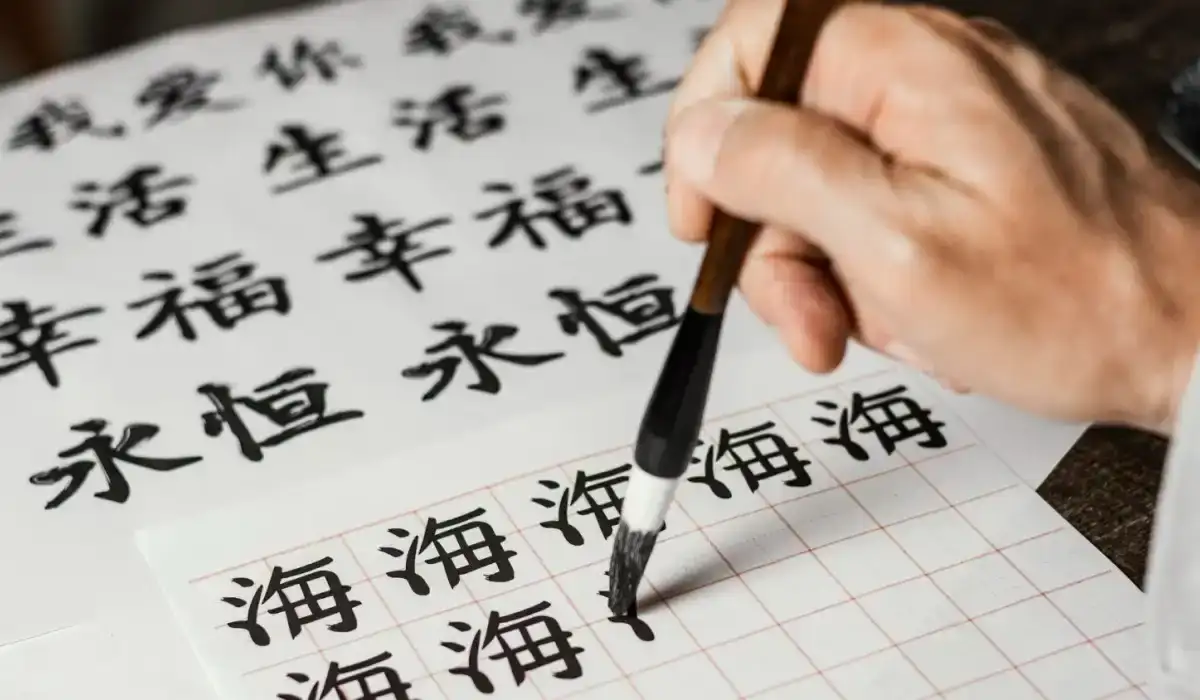Man writing Chinese symbols on white paper