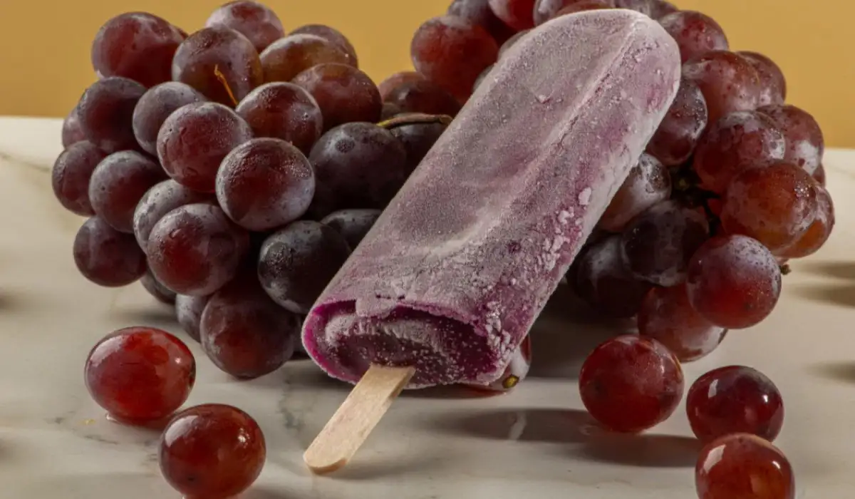 Grape ice cream on bunches of grapes on white background.