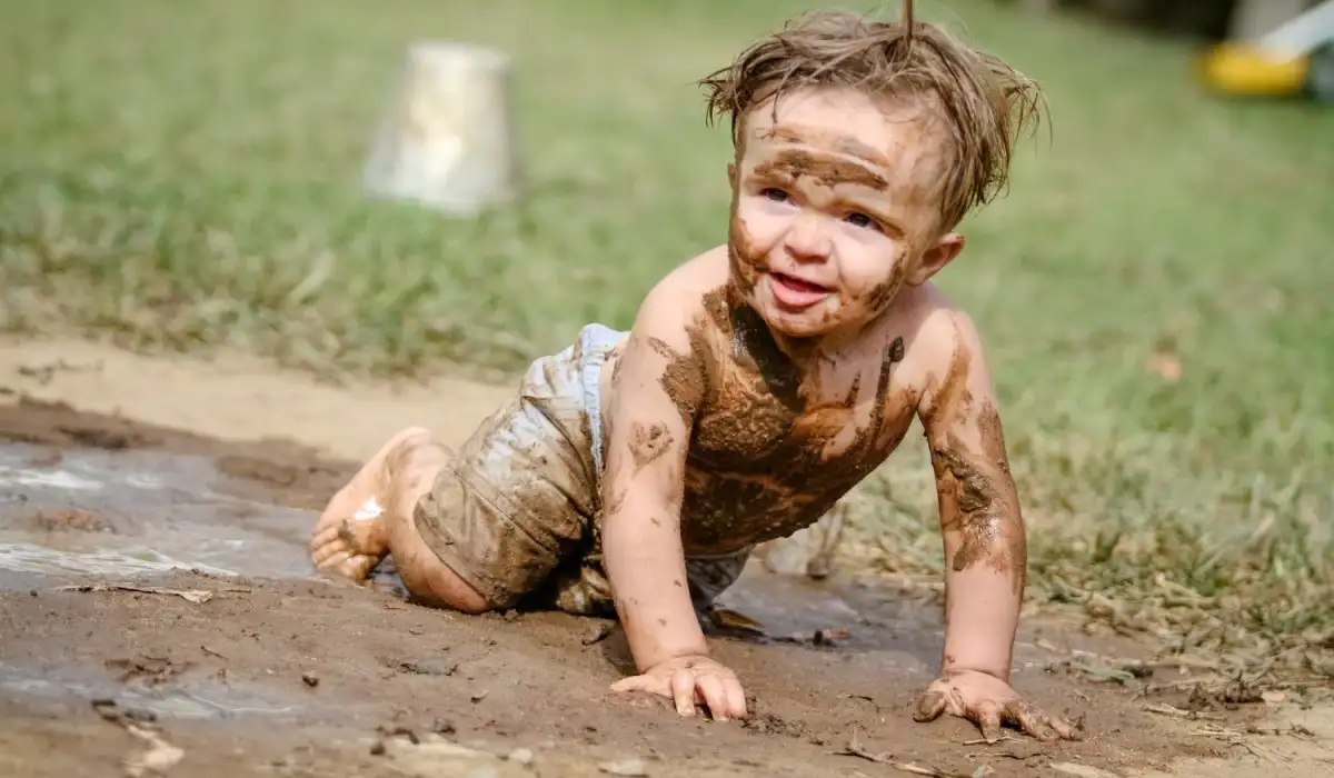Cute little boy playing in the mud
