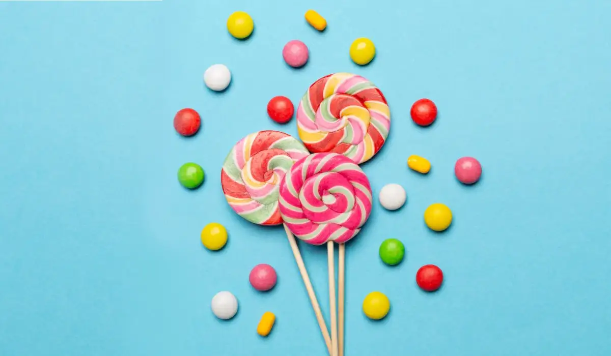 Some lollipops with other sweets scattered to the side, all on a blue background