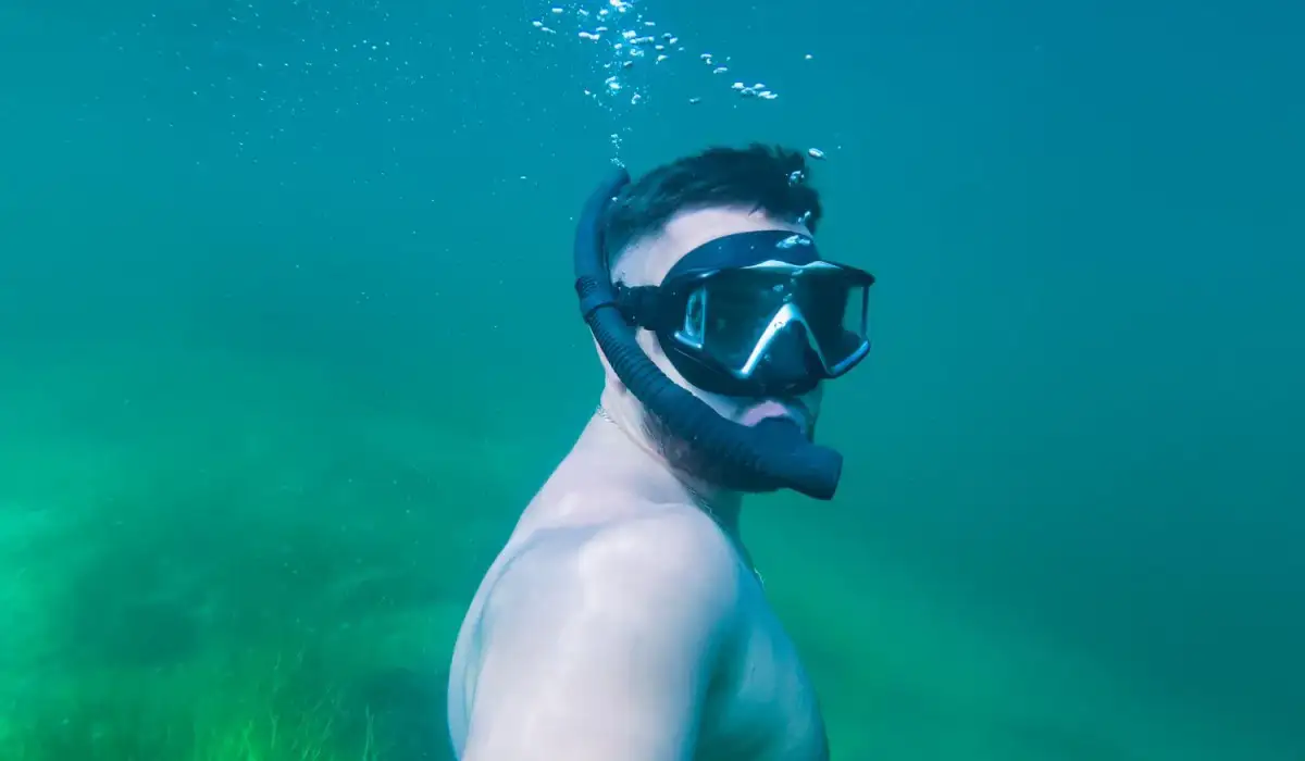 Underwater selfie of a man diving in the blue sea with a snorkel