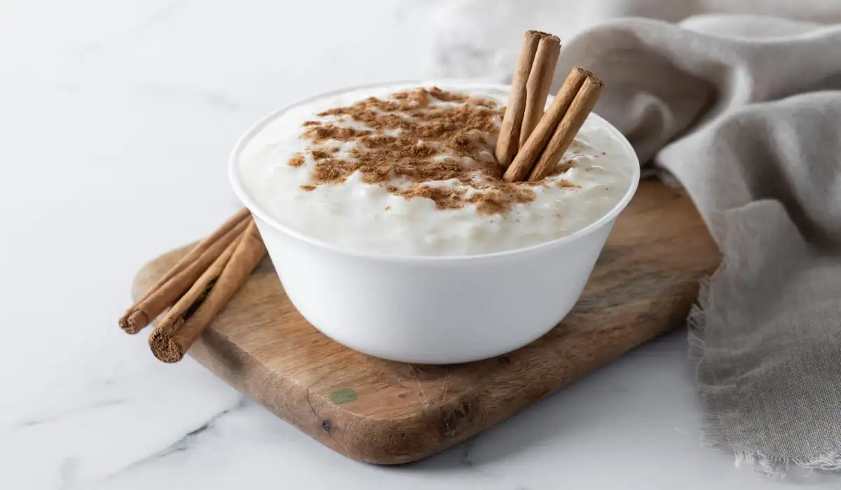 Rice pudding with cinnamon in clay bowl on white marble
