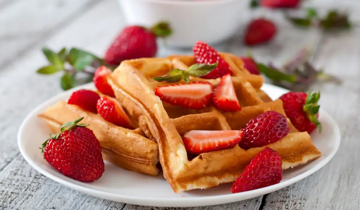Belgian waffles with strawberries and mint on a white plate