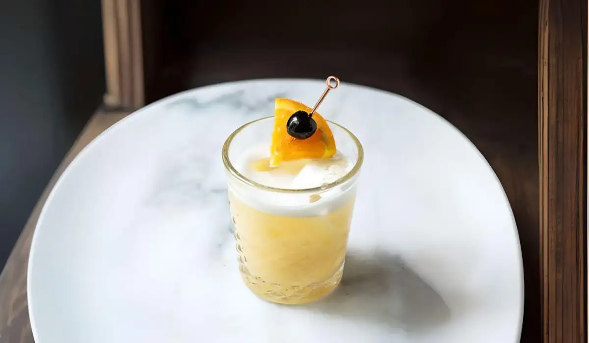 A glass of whiskey sour on a marble table