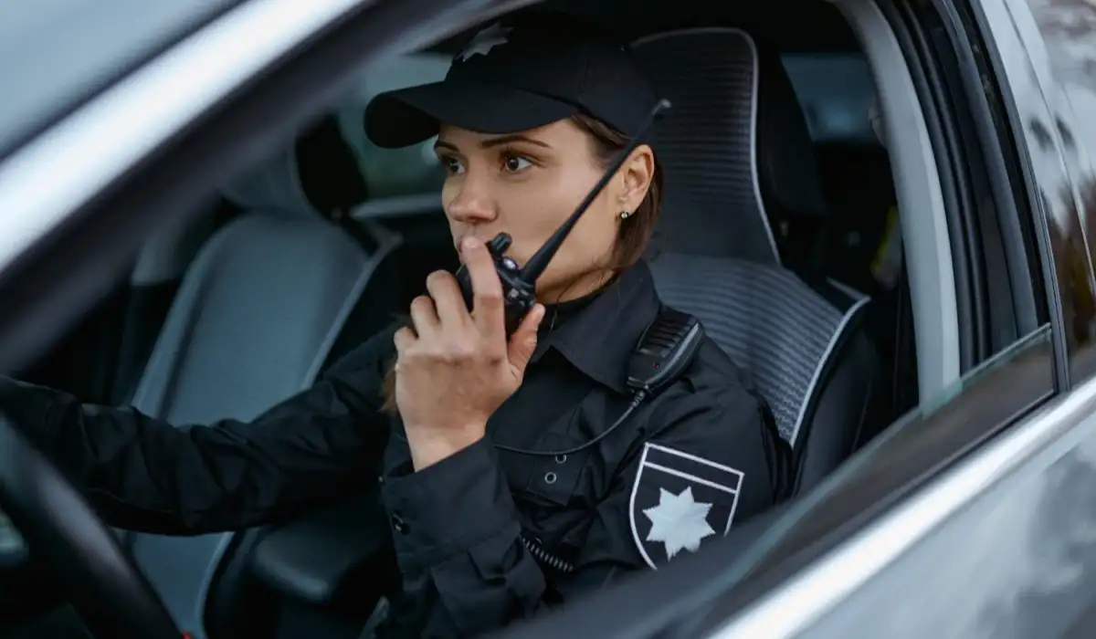 Policewoman using radio patrolling street in car