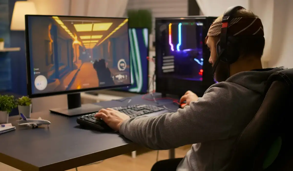 Man playing a first person video game using keyboard and headphones