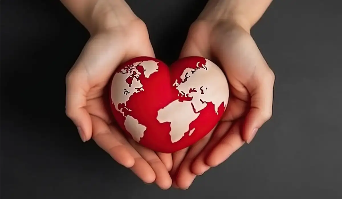 Hands holding a red heart shaped earth globe