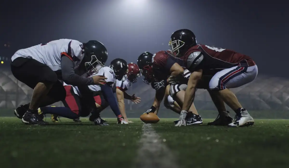 American football players are ready to start the game on the field at night