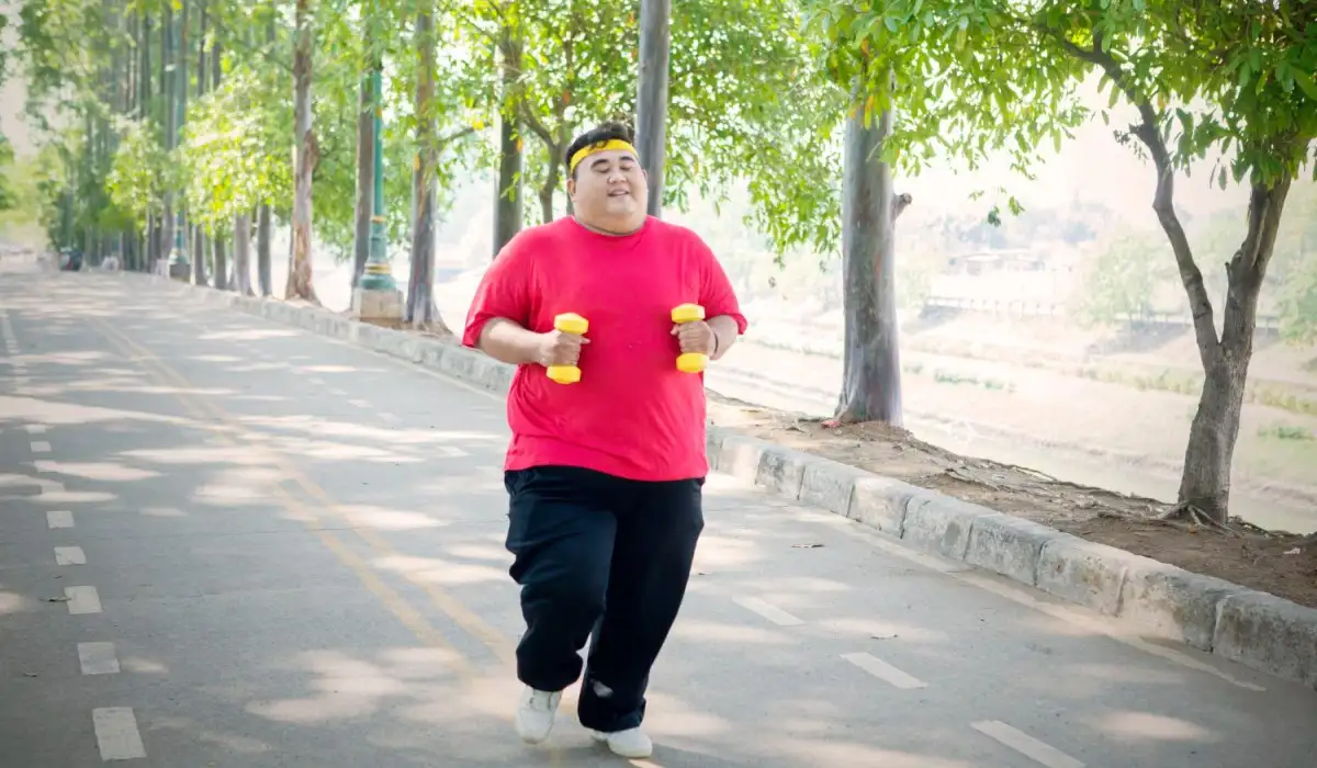 Young fat man running with dumbbells on the road