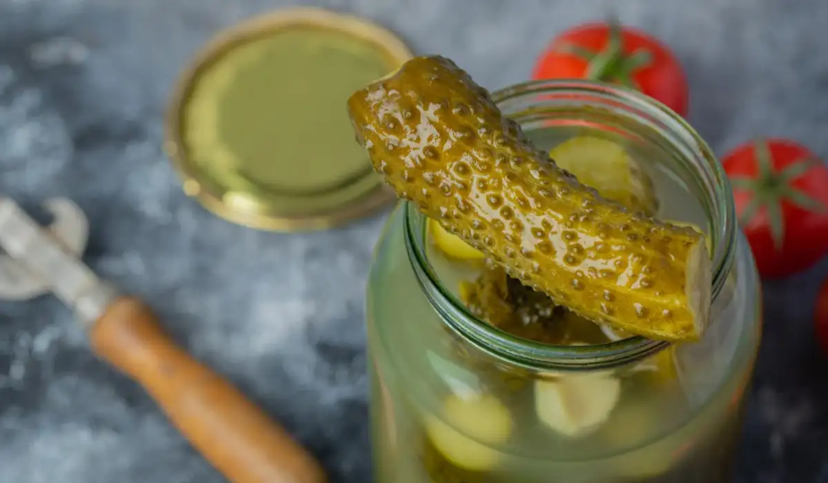 Open pickle jar with a pickle on the edge of the jar